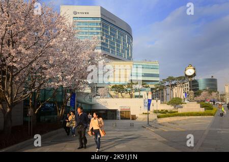 Ein tiefer Winkel einer frühlingshaften Straßenszene in Seoul mit Passanten, einem Universitätskrankenhaus und einem bewölkten Himmel vor Hintergrund, Südkorea Stockfoto