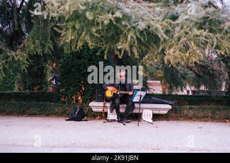 Ein männlicher Musiker, der in einem Park in Madrid, Spanien, singt und Gitarre spielt Stockfoto