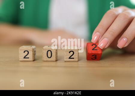 Weibliche Hand, die den Holzwürfelblock umdreht, ändern sich von 2022 auf 2023 Stockfoto