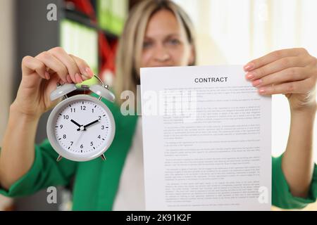 Geschäftsfrau mit Vertragsvertrag und Wecker Stockfoto