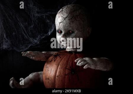 Zombie Puppe Porträt. Gruselig von Puppengesicht mit glühenden roten Augen und Zombie-Haut auf dem schwarzen Hintergrund. Halloween-Konzept. Stockfoto