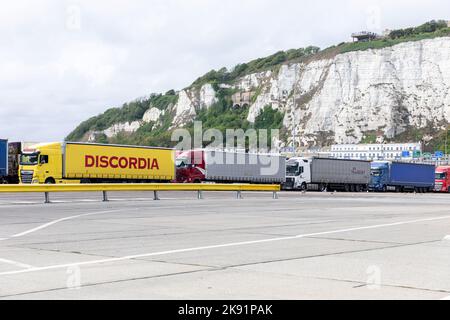 Güterkraftwagen, geparkt am Hafen von Dover. Ein gelber Discordia-Lastwagen davor.die weißen Klippen von Dover im Hintergrund.7.. September 2022 Stockfoto