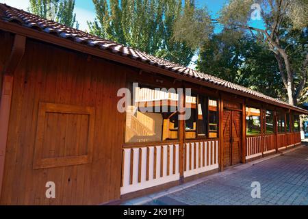 Holzrestaurant mit großen Fenstern an einem klaren, sonnigen Tag. Eine Struktur aus hellem gelbem und rotem Holz, in einem Park. Große Fenster spiegeln die Umgebung wider. Stockfoto