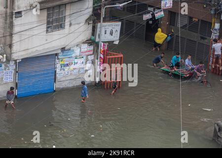 Dhaka, Bangladesch. 25. Oktober 2022. Rikscha-Besitzer kämpfen nach heftigen Regenfällen, die für Fußgänger und Pendler viel Leid verursachen, um durch eine wasserdurchflutete Straße zu waten. Der Zyklon Sitrang trifft Bangladesch, schnappt Kommunikations- und Stromverbindungen und überschwemmt Straßen, wodurch die Aktivitäten stillstehen. (Foto: Sazzad Hossain/SOPA Images/Sipa USA) Quelle: SIPA USA/Alamy Live News Stockfoto