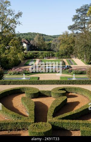 Das Chateau des Milandes, ehemaliges Wohnhaus von Josephine Baker in der Dordogne, ist ein Designergarten mit topiatrischer Hecke und Blumenränder Stockfoto