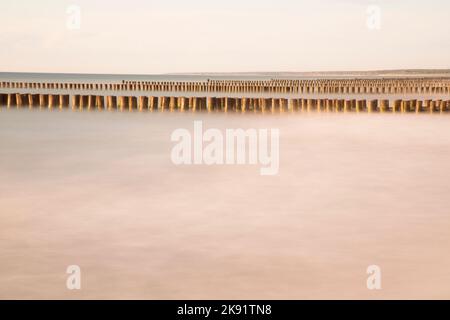 Reihen von Groynes in der ruhigen Ostsee Stockfoto