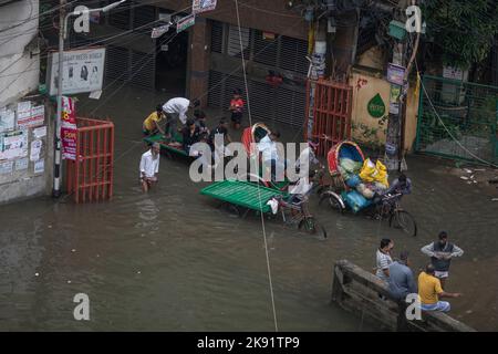 Dhaka, Bangladesch. 25. Oktober 2022. Rikscha-Besitzer kämpfen nach heftigen Regenfällen, die für Fußgänger und Pendler viel Leid verursachen, um durch eine wasserdurchflutete Straße zu waten. Der Zyklon Sitrang trifft Bangladesch, schnappt Kommunikations- und Stromverbindungen und überschwemmt Straßen, wodurch die Aktivitäten stillstehen. (Bild: © Sazzad Hossain/SOPA Images via ZUMA Press Wire) Stockfoto