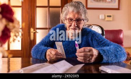 Alte Frau Auspacken Coronavirus Test Kit zu Hause. Kaukasische Großmutter, die Covid19 in ihrem Haus einen Schnelltest machte. Großmutter Quarantäne und Pandemie CO Stockfoto