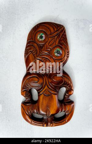 Maori Hei Tiki aus Holz, handgeschnitzt mit Paua-Muschelaugen. Neuseeländische Taonga. Weißer Hintergrund. Stockfoto