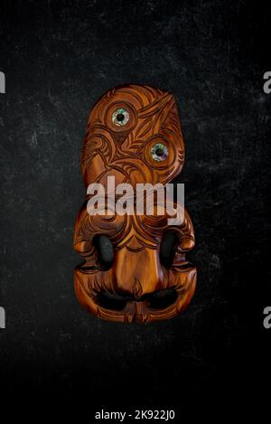 Maori Hei Tiki aus Holz, handgeschnitzt mit Paua-Muschelaugen. Neuseeländische Taonga. Stockfoto