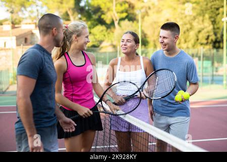 Vier Tennisspieler stehen auf dem Platz und reden über Match Stockfoto