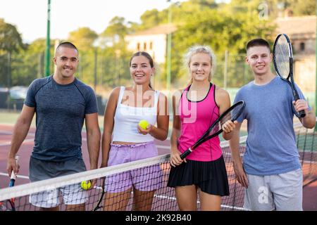 Zwei Paare junger Leute, die sich nach dem Tennisspiel unterhalten Stockfoto