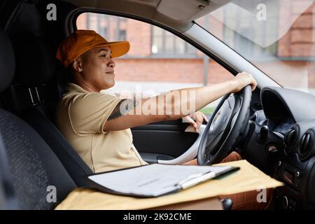 Seitenansicht Porträt einer jungen multiethnischen Frau, die einen Lieferwagen fährt und Uniform trägt Stockfoto