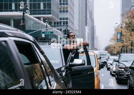 Ein Autofahrer, der wegen des Aussterbens im Verkehr stecken bleibt Rebellions Protest hält einen Flyer, der ihm von der Umweltgruppe übergeben wurde. Umweltaktivisten mit Aussterben Rebellion blockieren den Verkehr auf der Park Avenue in New York Citys Midtown. In Erwartung des zehnjährigen Jubiläums des verheerenden Hurrikan Sandy schwor eine Koalition von Umweltgruppen, die Park Avenue zu schließen, um mutige und dringende Maßnahmen zur Eindämmung des Klimawandels zu fordern. Fünfzehn Aktivisten wurden verhaftet. Fünfzehn Aktivisten wurden wegen Verkehrsbehinderungen verhaftet. (Foto von Olga Fedorova/SOPA Images/Sipa USA) Stockfoto