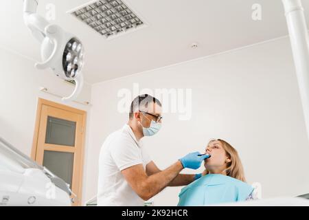 Arzt fügt Abdruckschale und Herstellung von Guss der Zähne an den Patienten in der Zahnmedizin vor der Zahnimplantation. Verfahren zur Erstellung von Zahnprothesen, c Stockfoto