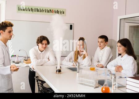 Vulkanexperiment. Die Chemielehrerin der Schule zeigt den Kindern Experimente im Labor. Bildungskonzept. Gruppenunterricht von Klassenkameraden in Chemie Stockfoto