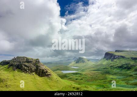 Wunderschöne, dramatische schottische Berglandschaft, zerklüftete Gipfel, kurvenreiche Straße und schiere Klippen, entlang der Quiraing Hills Walk, grüner Kurs Gras Covere Stockfoto
