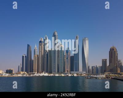 Stadtbild von hohen, modernen Gebäuden. Wolkenkratzer in Dubai Marina an einem hellen Sommertag. Klarer, blauer Himmel, ruhiges Wasser, Yachten, die an den Docks festgemacht sind. Stockfoto