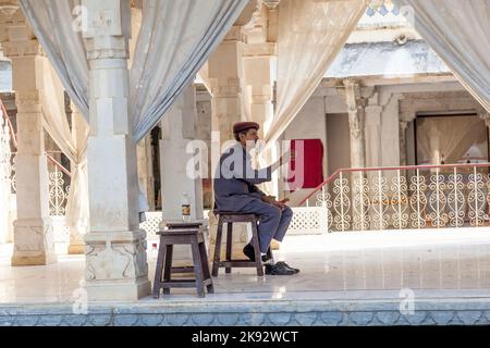 UDAIPUR, INDIEN - Okt 21, 2012: Wache sitzt auf einem Holzstuhl im Stadtpalast in Udaipur, Indien. Der Grundstein der Festung wurde 1559 von Udai gelegt Stockfoto