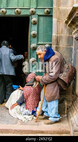 CUSZO, PERU - 16. JAN 2015: Obdachlose inderin bittet vor der Kirche in Cuzco, Peru, um Geld mit einem alten Bettler zu verdienen. Stockfoto