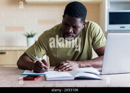 brasilianischer Mann verzweifelt Rechnungen für Zahlungen in der Küche zu überprüfen Stockfoto