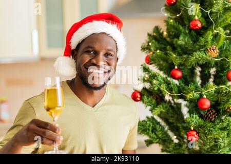 ein afroamerikanischer Mann hob ein Glas Champagner und toastet zu Hause Stockfoto