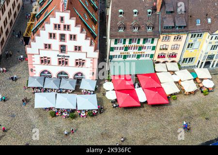 FREIBURG, DEUTSCHLAND - JUNI 28: Menschen auf dem alten Marktplatz in Freiburg, Deutschland. Die Fassade des alten Kornhauses stammt aus dem Jahr 1498. Stockfoto