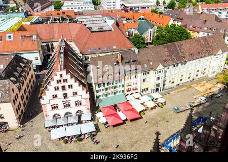 FREIBURG, DEUTSCHLAND - JUNI 28: Menschen auf dem alten Marktplatz in Freiburg, Deutschland. Die Fassade des alten Kornhauses stammt aus dem Jahr 1498. Stockfoto