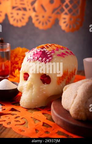 Zuckerschädel mit Pan de Muerto und Papel Picado. Dekoration traditionell in Altären für die Feier des Tages der Toten in Mexiko verwendet. Stockfoto