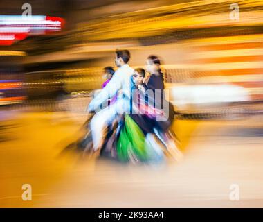 DELHI, INDIEN - 10. NOVEMBER 2011: Straßenverkehr in Delhi. Senior man transportiert die ganze Familie auf dem Motorrad in Delhi, Indien. Alte Gebäude und Auto Stockfoto