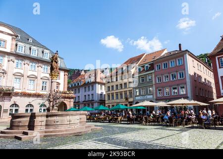 HEIDELBERG, DEUTSCHLAND - 7. JULI 2013: Menschen besuchen den Herkules Brunnen Heidelberg, Deutschland. Der Brunnen am zentralen Marktplatz wurde 1709 erbaut. Stockfoto