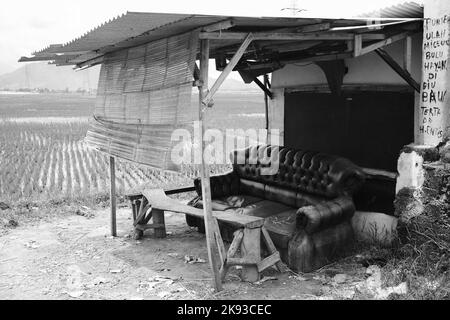 Schwarzweißfoto, Schwarzweißfoto eines zerbrochenen Sofas am Straßenrand in der Gegend von Cikancung - Indonesien Stockfoto