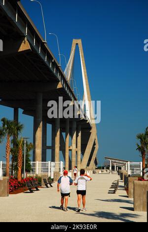 Die Menschen genießen einen gesunden Lebensstil, indem sie den Pfad und die Gärten unter der Arthur Ravenel Bridge in Charleston, South Carolina, entlang gehen Stockfoto