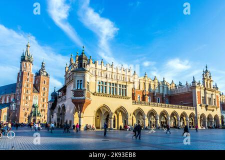 KRAKAU, POLEN - 7. Okt 2014: Menschen auf dem Hauptmarkt in der Nähe von Sukiennice, Tuchhalle und Rathausturm. Der Tuchsaal wurde im 14. Jahrhundert erbaut Stockfoto