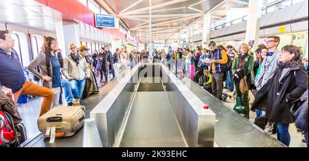 BERLIN, DEUTSCHLAND - 27. Okt 2014: Menschen warten am Gepäckband am Flughafen Tegel, Berlin. Es ist der viertgrößte Flughafen in Deutschland mit . o Stockfoto