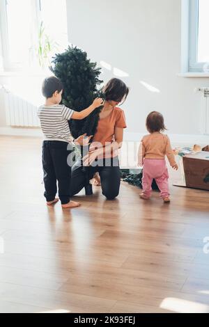 Familie genießt Weihnachten Montage eines künstlichen Weihnachtsbaum Dekoration des Hauses für die Winterferien. Glückliche Familie, Kindheit. Menschen Stockfoto