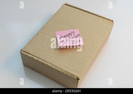 Paketbox mit einem Text Memo von Happy Birthday an Sie geschrieben auf einer Haftnotiz Stockfoto