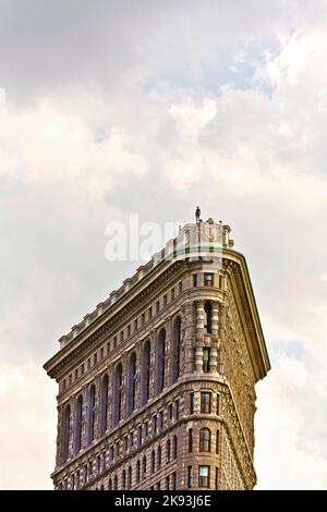 NEW YORK, USA - 7. JULI: Fassade des Flatiron Building am Nachmittag mit eiserner Menschenstatue auf dem Dach am 7,2010. Juli in New York, USA. Stockfoto