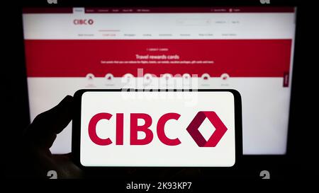 Person, die das Smartphone mit dem Logo der Canadian Imperial Bank of Commerce (CIBC) auf dem Bildschirm vor der Website hält. Konzentrieren Sie sich auf die Telefonanzeige. Stockfoto