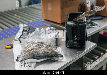 Köln, Deutschland. 21. Oktober 2022. Neben einem Toaster liegt eine Tüte Marihuana, in der die Tüte versteckt war. Auf der Suche nach Drogen prüft der Zoll jede Nacht mehrere hundert Pakete. Quelle: Marius Becker/dpa/Alamy Live News Stockfoto