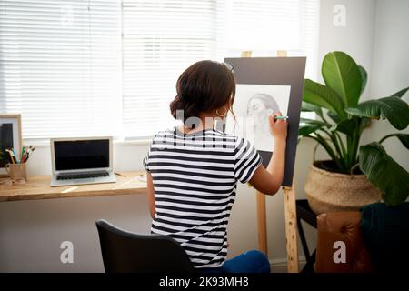 Manchmal müssen Sie zurück zum Zeichenbrett gehen. Rückansicht einer jungen Künstlerin, die ein Porträt einer Frau in ihrem Atelier zeichnet. Stockfoto