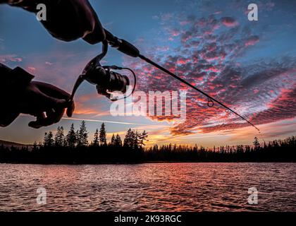 Fischer, die mit einer Angelrute, einer Angelrute, Laurentides, Quebec, Kanada, see, Sonnenuntergang, roter Himmel Stockfoto