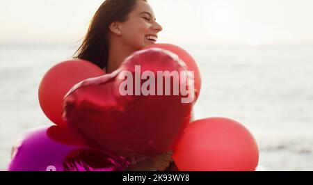 Glück beginnt mit Ihnen. Eine schöne junge Frau mit herzförmigen Ballons. Stockfoto