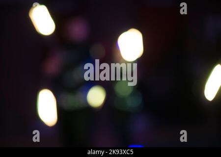 Weiße Bokeh-Flecken auf einem dunklen Hintergrund einer Nachtstadt. Stockfoto