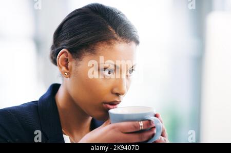 Fokus ist ein Schlüsselfaktor für den Erfolg. Eine junge Geschäftsfrau konzentriert sich am Computer und beim Kaffee in einem modernen Büro. Stockfoto
