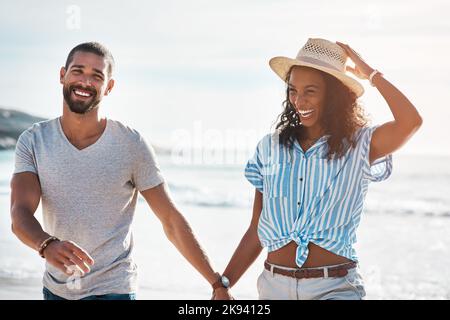 Gemeinsam haben wir den größten Spaß. Ein junges Paar, das am Strand entlang läuft. Stockfoto