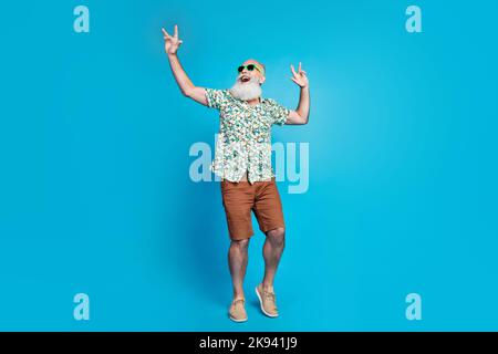 Ganzkörperfoto des alten Rentners bärtiger grauer Schnurrbart Ehemann tragen tropisches Sommerhemd Hände Rock Roll Blick auf isoliert auf blaue Farbe Stockfoto