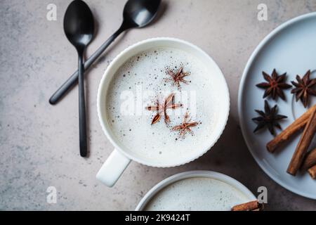 Hausgemachter Chai Latte mit Zimt und Sternanis in einer weißen Tasse, Draufsicht, dunkler Hintergrund. Stockfoto