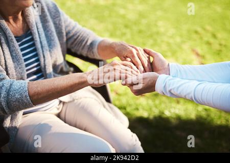 Ich bin hier für Sie. Eine unkenntliche Frau, die eine ältere Frau in den Händen hält. Stockfoto