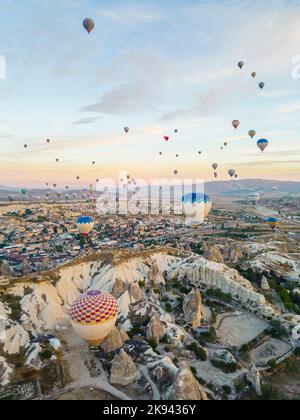 Wunderschöne Luftaufnahme von Dutzenden farbenfroher Luftballons, die über die felsige Landschaft von Kappadokien fliegen. Hochwertige Fotos Stockfoto